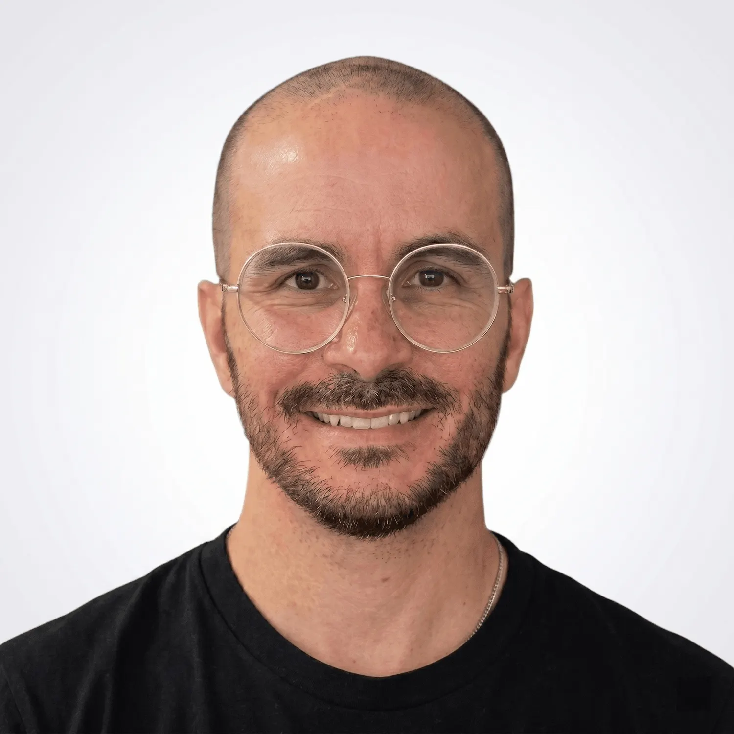 Oriol López smiling, wearing round glasses and a black t-shirt