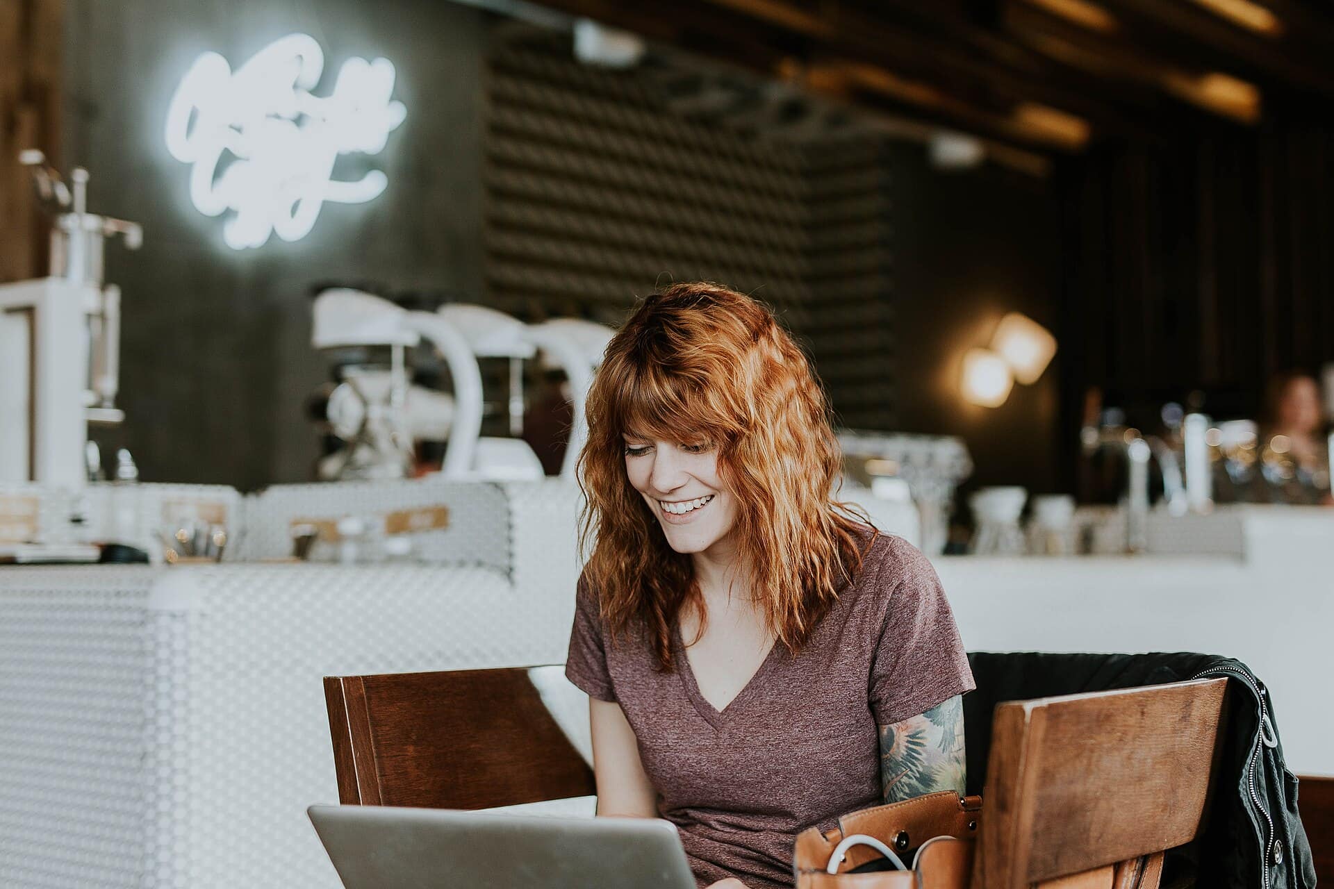 A business owner smiling at her laptop in a café.
