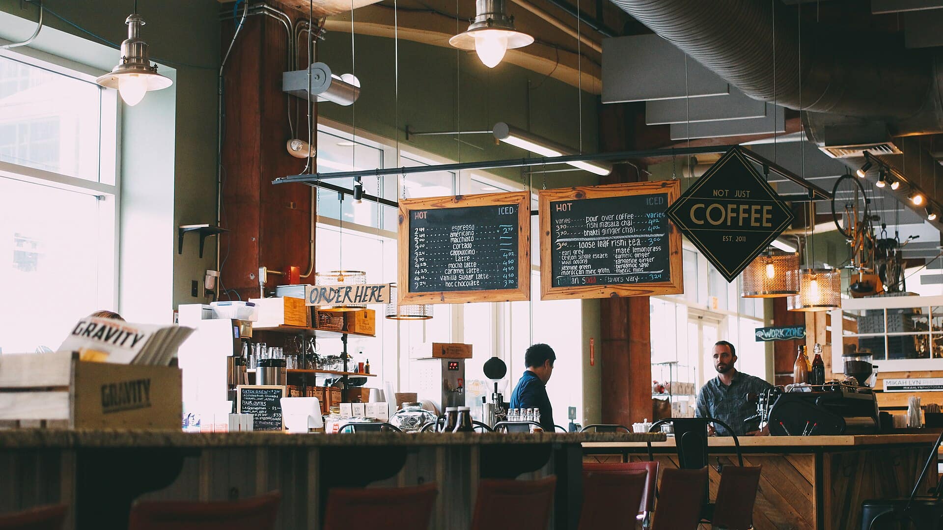 Owners serving customers at the counter of a small coffee shop.
